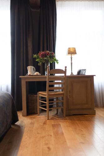 a bedroom with a desk and a chair with a vase of flowers at Hotel Boterhuis in Bruges
