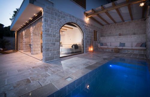 einen Außenpool mit einer Steinmauer und einer Terrasse in der Unterkunft Apartments Vela Sollis in Marusici 