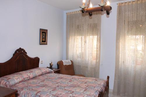 a bedroom with a bed and two windows with curtains at Casa De La Virginia in Valdealgorfa
