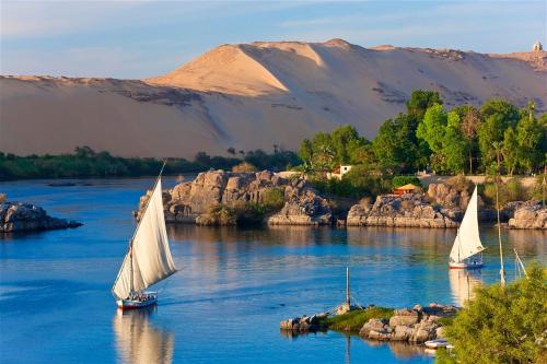three sailboats on a river with mountains in the background at Basma Executive Club in Aswan
