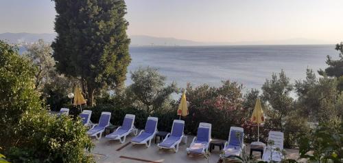 Gemlik的住宿－阿塔邁爾多加度假酒店，一排椅子和遮阳伞与海洋