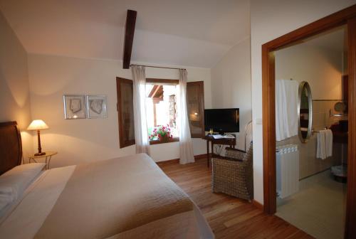a bedroom with a bed and a window and a television at Hotel Del Verde Al Amarillo in Peñasrubias de Pirón