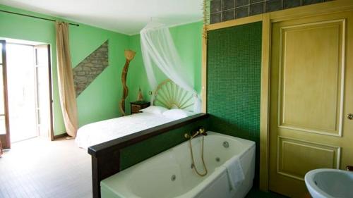 een groene badkamer met een bad en een bed bij Locanda degli Sfizi in Cravanzana