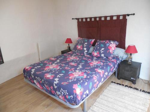 Un dormitorio con una cama con una colcha floral. en Les Gites Du Mazel, en champis