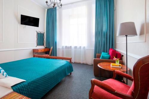 una habitación de hotel con una cama azul y sillas en Iskra Hotel, en San Petersburgo