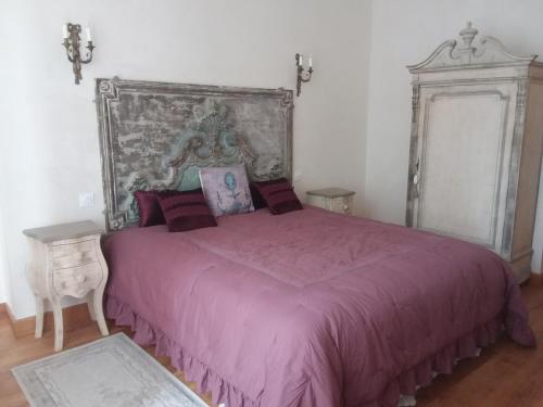 ein Schlafzimmer mit einem großen Bett mit einer lila Tagesdecke in der Unterkunft Manoir de la Camusière in Unverre