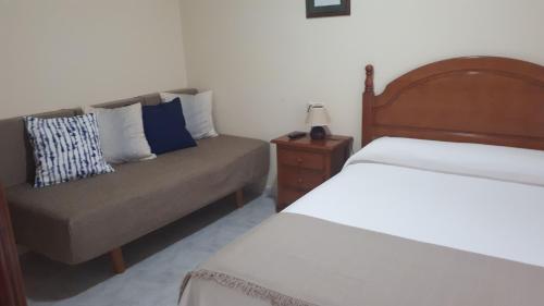 a bedroom with a couch and a bed and a chair at AS VIÑAS in O Grove