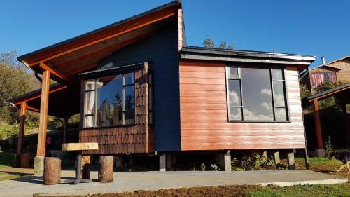 a small house with a black and wooden exterior at Hotel y Cabañas Terrazas Vista al Mar hct in Ancud