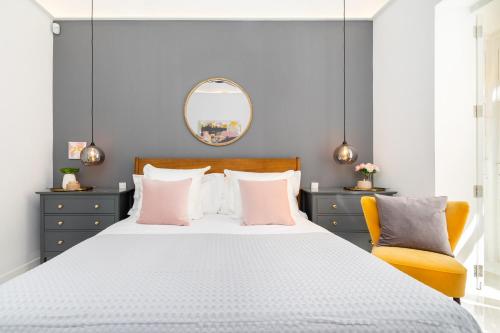 a bedroom with a white bed with pink pillows and a mirror at Amazing Art Deco Villa 150m to sea with Daily Housekeeping in Sliema