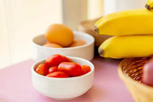 a table with bowls of tomatoes and bananas on it at Ethrion in Ermoupoli
