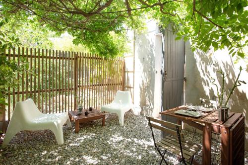 d'une terrasse avec 2 chaises blanches, une table et une clôture. dans l'établissement GregBnb - Studio CLIMATISÉ - Terrasse & parking privé, à Toulon