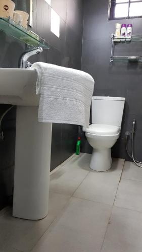 a bathroom with a white sink and a toilet at CHARAKAMA Guest Bungalow - GAMPAHA in Gampaha