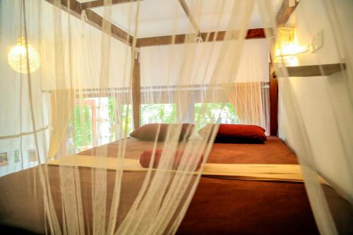 een slaapkamer met een hemelbed en gordijnen bij Chez Podi Surf Stay in Mirissa