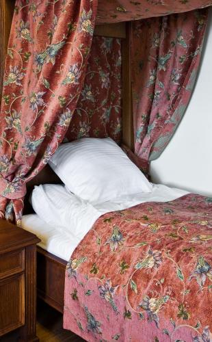 a bed with a red canopy and white pillows at Zamek Golubski in Golub-Dobrzyń