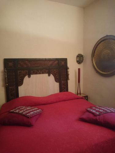 - une chambre avec un lit rouge et une tête de lit en bois dans l'établissement Chambre Voyage du Mas des Fontaines, à Montagnac