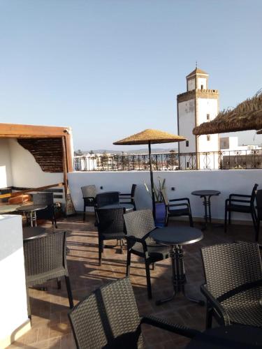 a patio with tables and chairs and a lighthouse at Appart, Hotel & Café Agadir in Essaouira