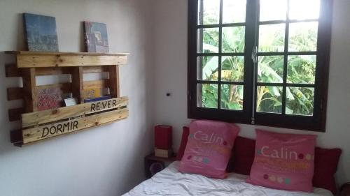 Un dormitorio con una cama con almohadas rosas y una ventana. en Oiseaux du Paradis, en Le Tampon