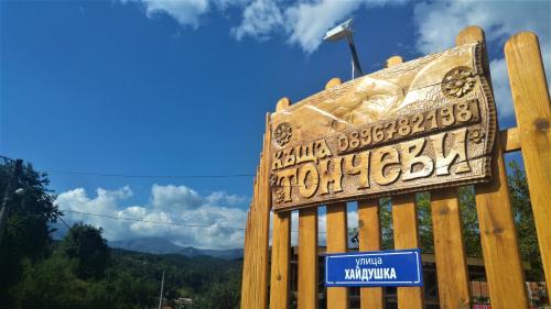 a sign on a wooden fence with mountains in the background at Стаи за гости - Къща ТОНЧЕВИ in Kalofer