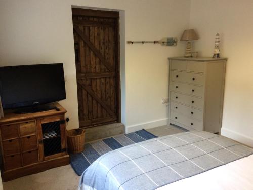 a bedroom with a bed and a tv and a door at Guest Suite at 31 Little England in Milborne Saint Andrew
