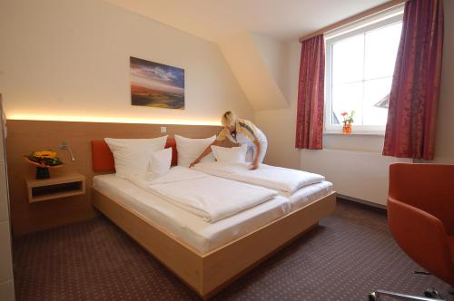 una mujer sentada en una cama en una habitación de hotel en Landhotel Behre en Lehrte