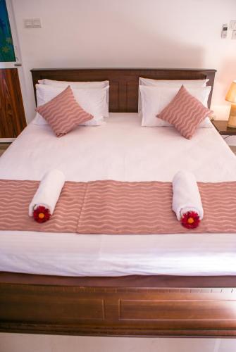 a bed with two pillows and red flowers on it at BIVORA Villa in Negombo