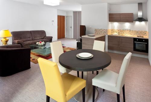 a kitchen and a living room with a table and chairs at La Résidence Therm’Appart in Vichy