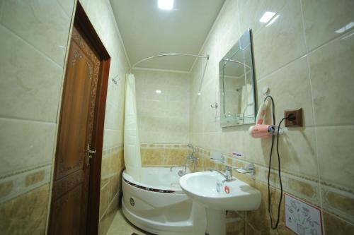 La salle de bains est pourvue d'un lavabo, de toilettes et d'un miroir. dans l'établissement Rasulboy Guest House, à Khiva