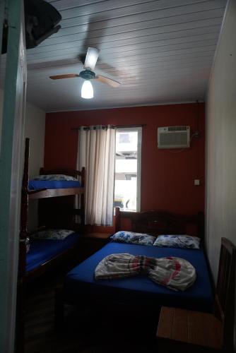 a bedroom with two beds and a ceiling fan at Pousada Orquidário in Santos