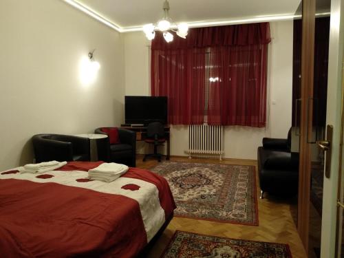a bedroom with a bed and chairs and a television at Gyöngyi apartman in Budapest