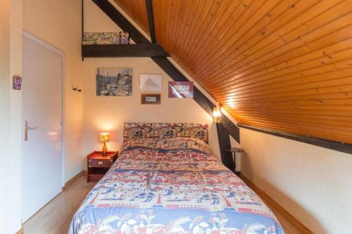 Un dormitorio con una cama grande con techo de madera. en La Petite Londe, en Biéville-Beuville