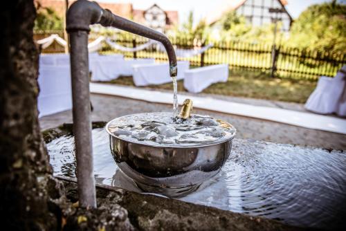 a faucet pouring water into a metal bowl at Romantik Hotel Ahrenberg in Bad Sooden-Allendorf
