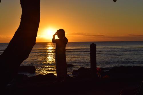 a person standing on the beach talking on a cell phone at Belle Crique D3 Tamarin Ile Maurice in Tamarin
