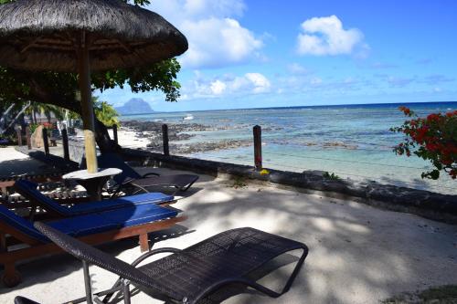 a beach with chairs and an umbrella and the ocean at Belle Crique D3 Tamarin Ile Maurice in Tamarin