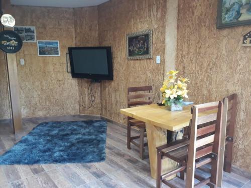 une salle à manger avec une table et une télévision dans l'établissement Chácara Águas Claras, à Monte Sião