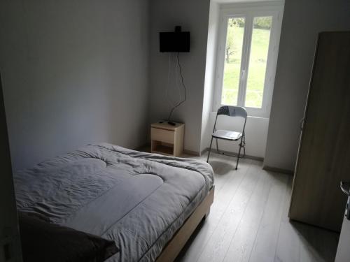 sypialnia z łóżkiem, krzesłem i oknem w obiekcie Maison à la campagne au cœur du Cantal dept 15 w mieście Marmanhac