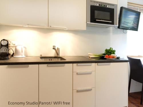 a kitchen with white cabinets and a sink at Zermatt Appartements in Zermatt