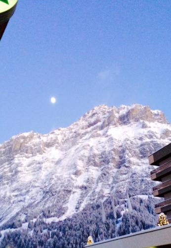 a mountain covered in snow with the moon in the sky at Luxury, new - amazing views Grindelwald Eiger Jungfrau Mönch in Grindelwald
