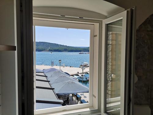 a window view of a dock with boats in the water at Apartmani Kraj mora in Cres