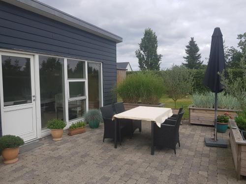 un patio con una mesa blanca y sillas frente a una casa en 1 room with private Bath en Allingåbro
