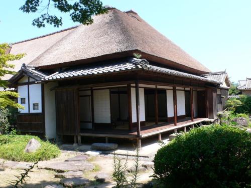 a small house with a thatched roof and a yard at Guesthouse RETURN in Kitsuki