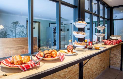 een buffet met brood en zoete deegwaren op een tafel bij Hôtel Moustache Lille - Seclin in Seclin