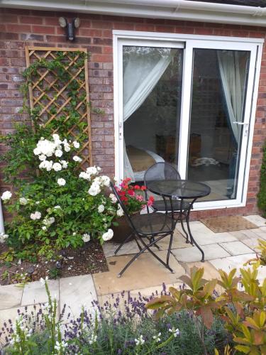 a patio with a table and flowers in front of a house at Offa Hideaway in Leamington Spa