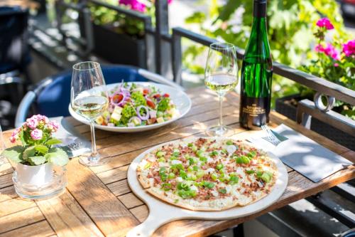 a table with two pizzas and a salad and a bottle of wine at Hotel Karl Müller in Cochem