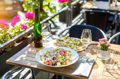 a table with a plate of salad and wine glasses at Hotel Karl Müller in Cochem