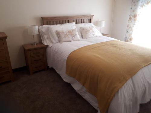 a bedroom with a large bed with white sheets and pillows at Llandeilo Farmhouse in Llandeilo