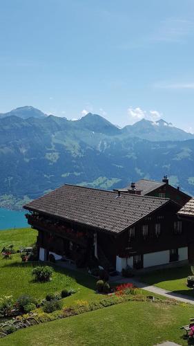 a house on a hill with mountains in the background at App. Seeblick Top of Interlaken in Beatenberg