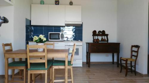 a kitchen with a table and chairs and a microwave at La Peonia casa vacanze in montagna prato verde panorama stupendo Sardegna in Seùlo
