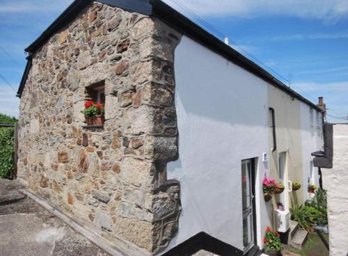 a stone building with a window and flowers on it at Harbour Lights in Penzance