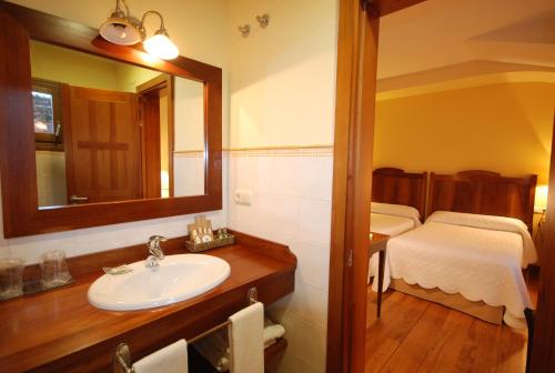a bathroom with a sink and a mirror and a bed at Hotel Del Verde Al Amarillo in Peñasrubias de Pirón