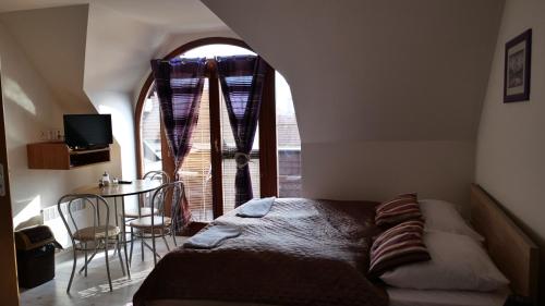 a bedroom with a bed and a table and a window at Penzion Real in Žiar